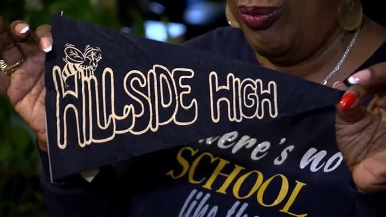  woman holds up Hillside High pennant